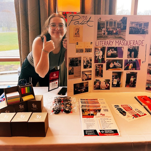 Brianna Chapman beside the SHSU Sigma Tau Delta chapter's display.