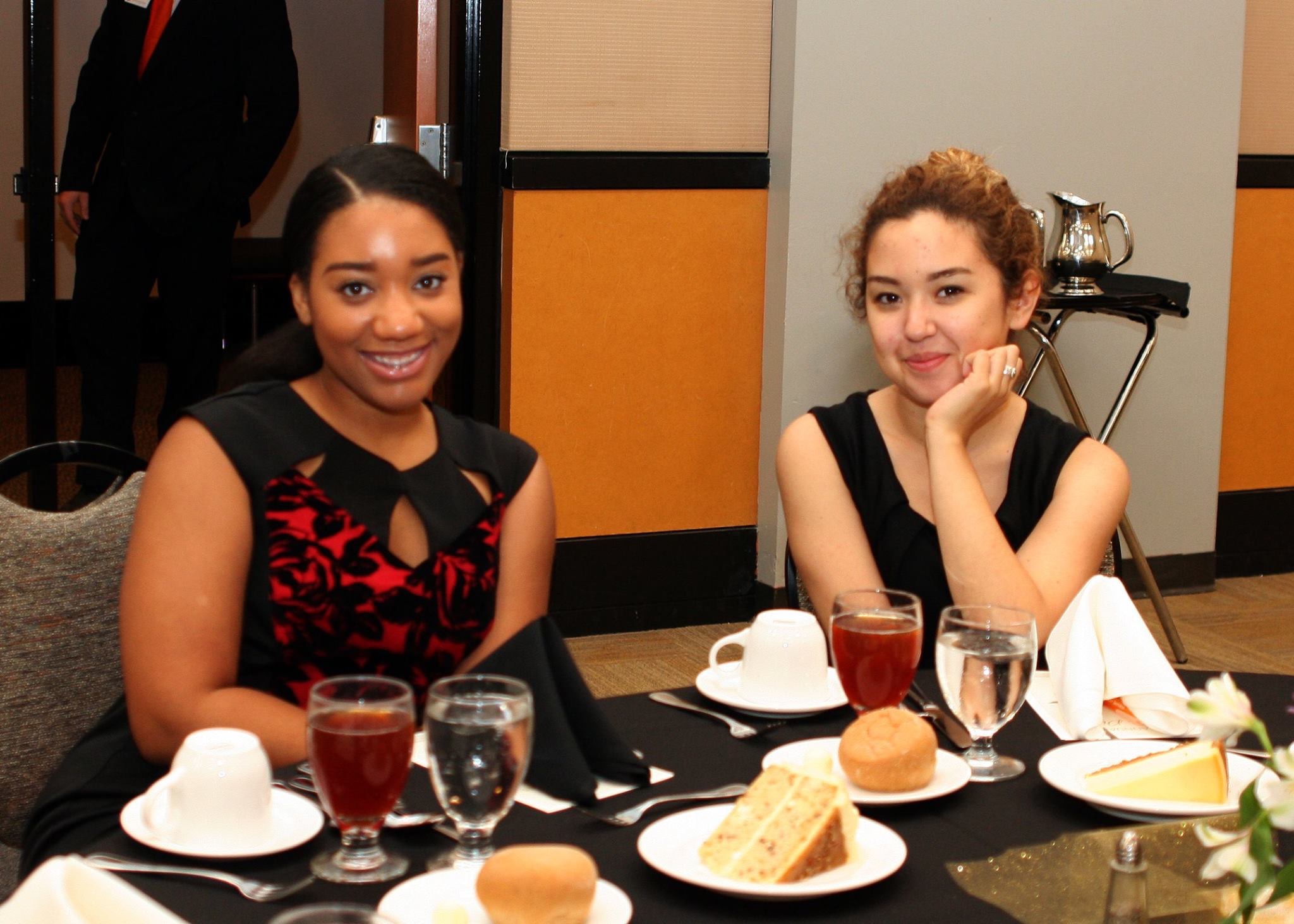 Two women dressed professionally smile for the camera.