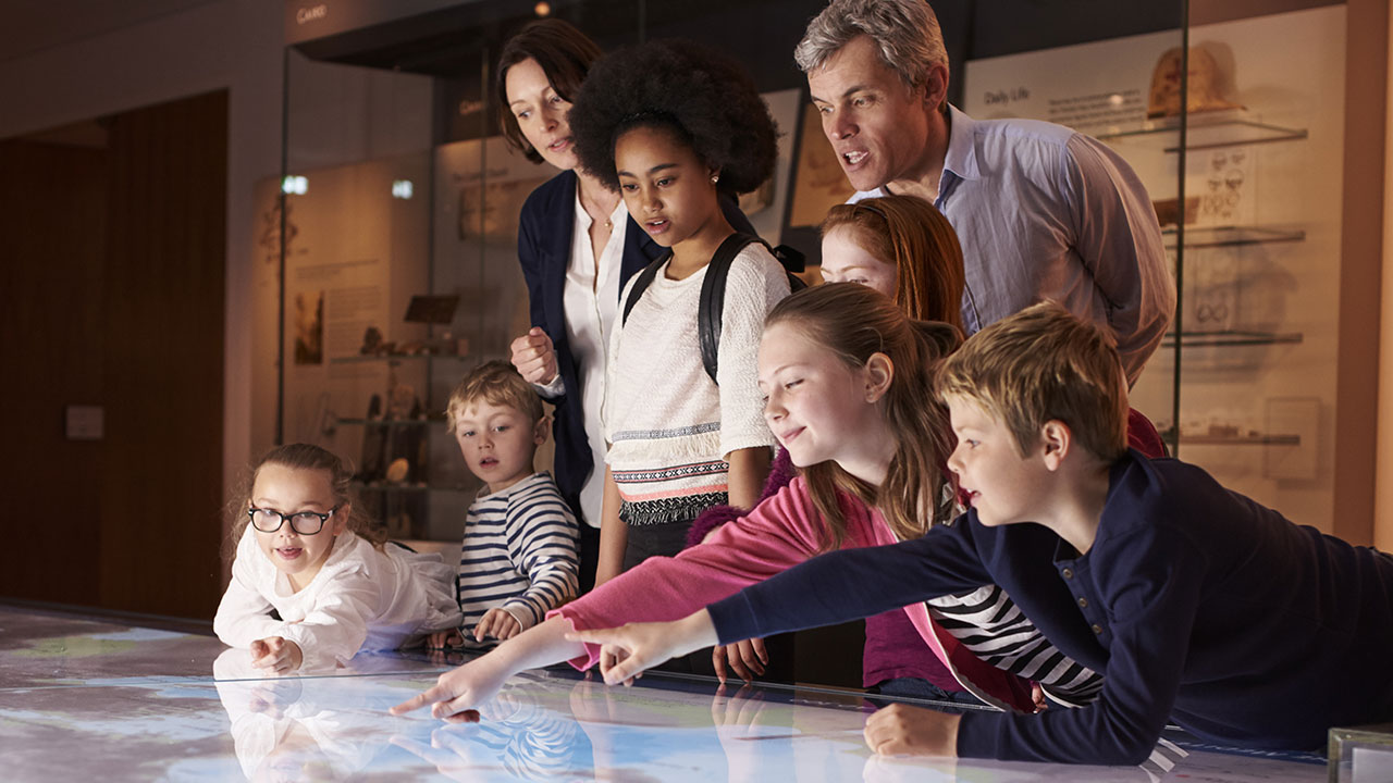 Teachers and students looking at a virtual map while on a tour at a history museum.