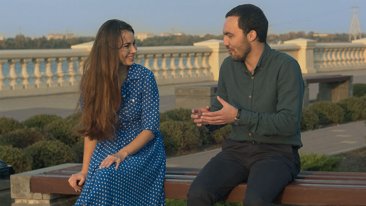 Two people on a bench holding a conversation.