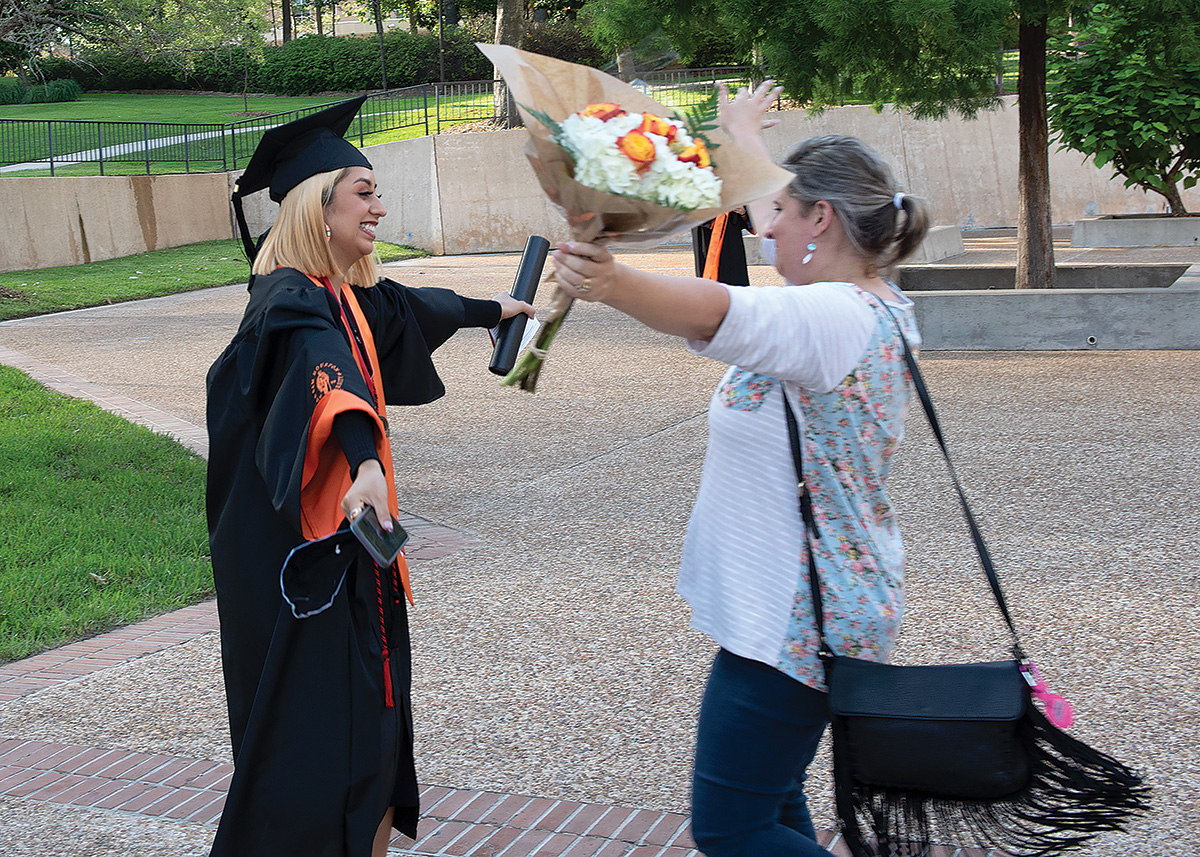 Brenda Cruz-Flores and LaShawna Rhoden run toward each other to embrace during graduation at Bernard G. Johnson coliseum.