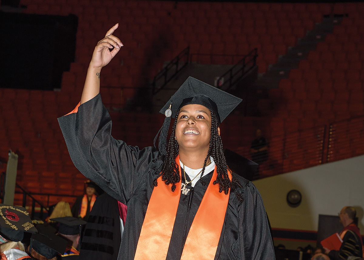 One SHSU alumni holds up her dog. Another holds an award.