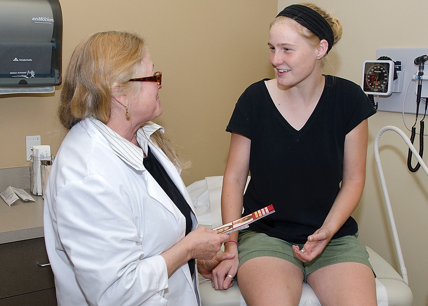 A doctor handing a student a brochure in the Student Health Center.