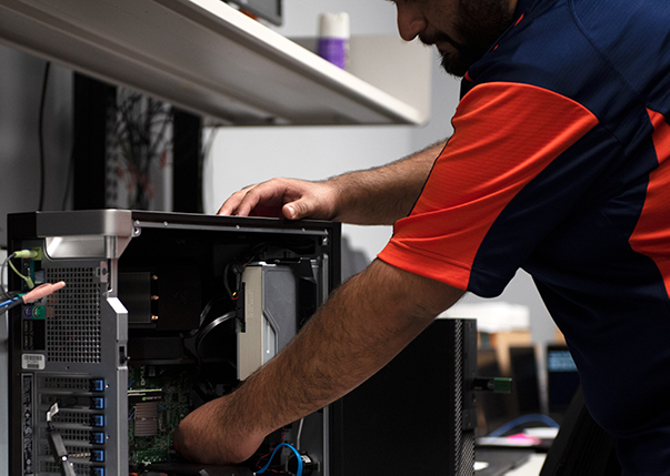 An IT@Sam employee works on the internal parts of a computer.