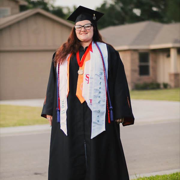 Star poses proudly in her graduation gown adorned with honor cords.