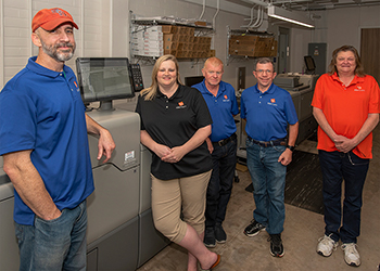 The Print Services Crew posing with their printer.